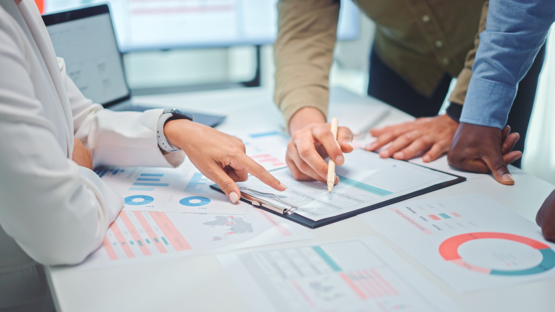 Close up of a multiethnic team of developers pointing to a graph with marketing data analysis.